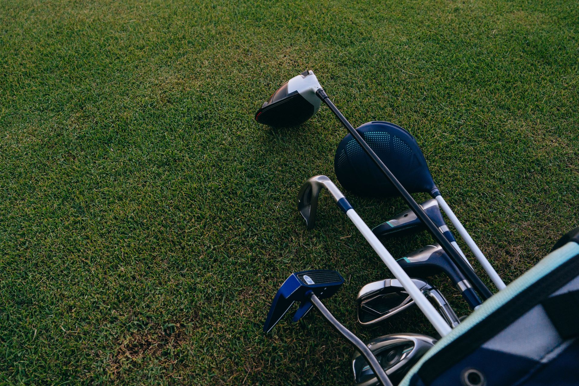Close-up of golf clubs on a green lawn, ideal for golfing enthusiasts.